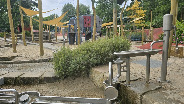 Gerade in heißen Sommern eine wichtige Abkühlung für die Kleinen: ein Wasserspielplatz. Das Bild zeigt einen Wasserspielplatz ohne Kinder.