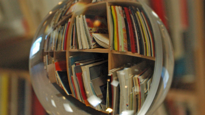 Das Bild zeigt ein Bücherregal durch eine Glaskugel betrachtet´.