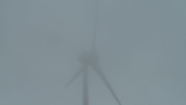 Das Bild zeigt ein Windrad im Nebel.