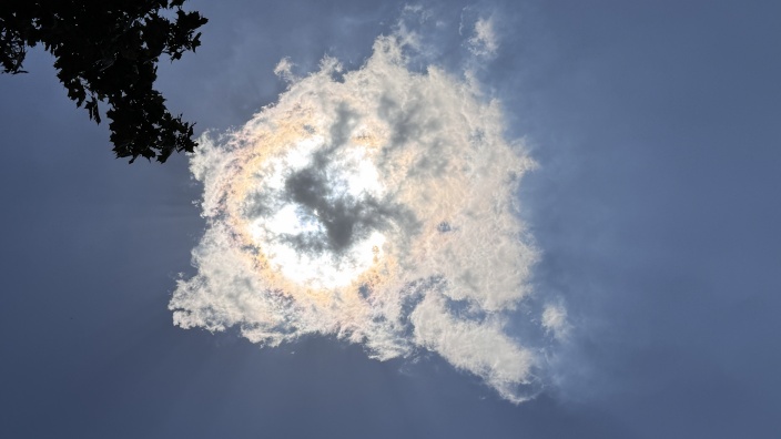 Das Symbolbild zeigt die Sonne hinter einer Wolke.