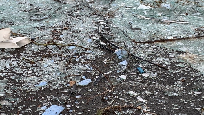 Das Bild zeigt Glasscherben auf Asphaltboden.