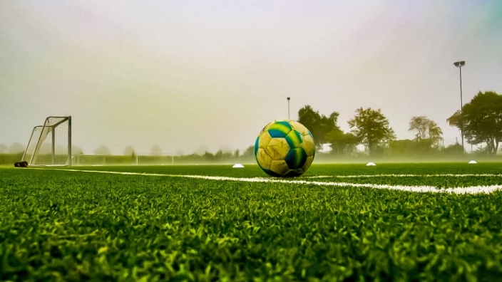 Das Symbolfoto zeigt einen Fußball auf einem Sportplatz.