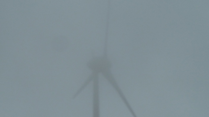 Das Bild zeigt ein Windrad im Nebel.